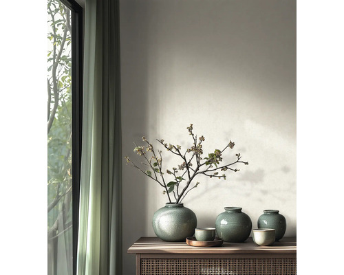 Ronde keramische vazen met craquelé glazuur en takken op een houten sidetable in een modern ingerichte kamer naast een raam.