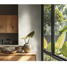 Lichte keuken met houten kasten, keramische kommen en een vaas op een houten werkblad voor een groot raam met uitzicht op planten.