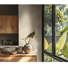 Lichte moderne keuken met houten kasten, keramieken schalen, een vaas en een groot raam met uitzicht op de tuin.