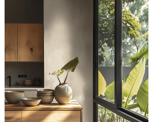 Lichte moderne keuken met houten kasten, keramieken schalen, een vaas en een groot raam met uitzicht op de tuin.