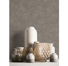 Vliesbehang met linnenstructuur in bruingrijs, gedecoreerd met diverse vazen van keramiek en glas.