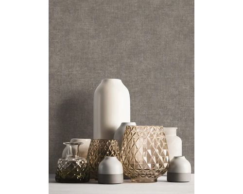 Vliesbehang met linnenstructuur in bruingrijs, gedecoreerd met diverse vazen van keramiek en glas.