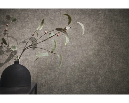 Gestructureerd behang met linnenlook met een zwarte vaas en takken op de voorgrond.