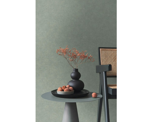 Wand met getextureerd behang in een modern ingerichte kamer met bijzettafel, vaas en stoel met vlechtwerk.