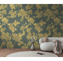 Behang met geel bloemenpatroon op een donkergroene achtergrond in een lichte woonkamer met een witte bank en een rond tapijt.