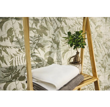 Vliesbehang met botanisch bladerpatroon, met daarvoor een houten rek met handdoeken en een kamerplant.