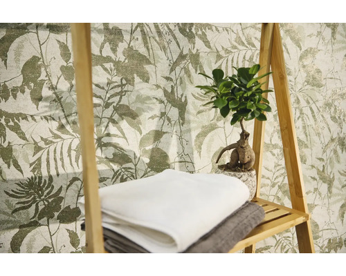 Vliesbehang met botanisch bladerpatroon, met daarvoor een houten rek met handdoeken en een kamerplant.