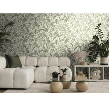 Lichte woonkamer met behang met botanisch patroon, witte modulaire bank, een glazen tafel met stenen bollen en diverse kamerplanten.