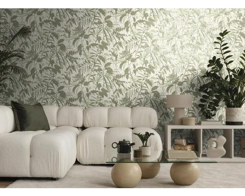 Lichte woonkamer met behang met botanisch patroon, witte modulaire bank, een glazen tafel met stenen bollen en diverse kamerplanten.