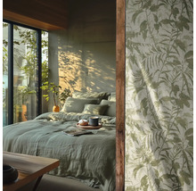 Slaapkamer met lichtgroen linnen beddengoed en behang met botanisch bladerpatroon voor een zonnig raam.