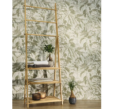 Vliesbehang met botanisch bladmotief en vogels achter een bamboe rek met handdoeken en planten in een lichte kamer.
