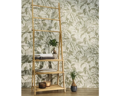 Vliesbehang met botanisch bladmotief en vogels achter een bamboe rek met handdoeken en planten in een lichte kamer.