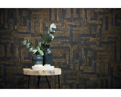 Vliesbehang met abstract geometrisch patroon in weeflook achter een bijzettafel met vazen en eucalyptustakken.