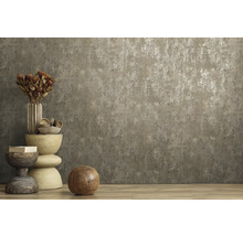 Vliesbehang met betonlook en metaaleffect in een kamer met houten vloer en decoratie.