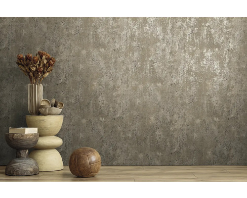 Vliesbehang met betonlook en metaaleffect in een kamer met houten vloer en decoratie.