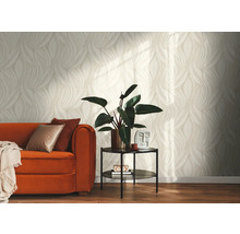 Lichte woonkamer met behang met beige bladpatroon, een oranje bank met kussens en een bijzettafel met kamerplant.