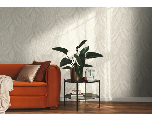 Lichte woonkamer met behang met beige bladpatroon, een oranje bank met kussens en een bijzettafel met kamerplant.