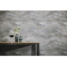 Gestructureerd vliesbehang met steenlook op een muur achter een houten tafel met decoratieve vazen en een wijnglas.