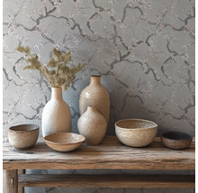 Rustieke decoratie met keramieken vazen en schalen op een houten bank voor behang met bloesemtakken.