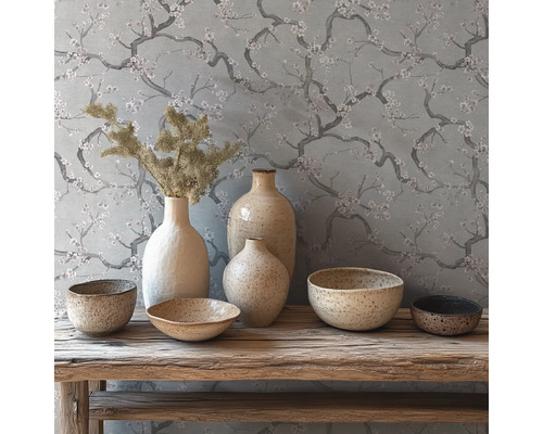 Rustieke decoratie met keramieken vazen en schalen op een houten bank voor behang met bloesemtakken.