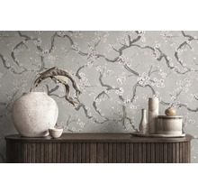 Behang met een bloemenpatroon van takken met bloesem achter een houten dressoir met decoratieve vazen.