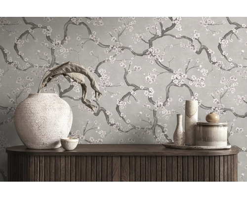 Behang met een bloemenpatroon van takken met bloesem achter een houten dressoir met decoratieve vazen.