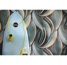 Behang met groot, gestileerd bladerpatroon in blauwgroen en bruin naast een lichtblauwe surfplank.