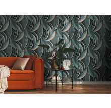 Vliesbehang met golvend bladmotief in een woonkamer met een oranje bank en kamerplant.