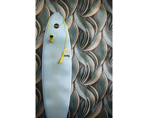 Vliesbehang met gestileerd bladerpatroon in groen en beige, met daarvoor een lichtblauwe surfboard met gele leash.