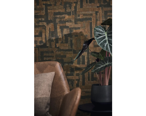 Vliesbehang met abstract geometrisch patroon in weefoptiek achter een bruine leren fauteuil en een kamerplant.