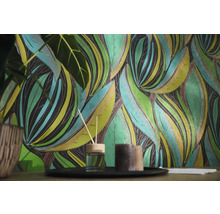 Vliesbehang met botanisch bladpatroon in een woonkamerscène met geurverspreider en kaarsen.