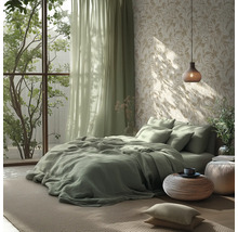 Lichte slaapkamer met groen beddengoed, behang met bladpatroon, lichtgroene gordijnen en een geweven hanglamp en poefs.