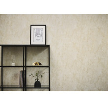 Vliesbehang in beige betonlook op een muur achter een zwart metalen rek met decoratieve objecten.