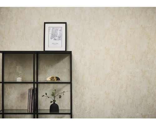 Vliesbehang in beige betonlook op een muur achter een zwart metalen rek met decoratieve objecten.