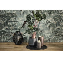 Vliesbehang met jungle-motief en vintage-structuur achter een Alocasia-plant in keramische pot en een roosterlantaarn op houten oppervlak.