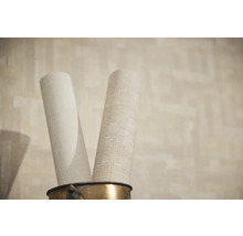 Twee rollen behang met verschillende structuren en texturen in een metalen houder.