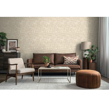 Woonkamer met een licht vliesbehang met geometrisch patroon, bruine leren bank, fauteuil en salontafel.