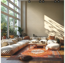 Lichte woonkamer met grote hoekbank, houten tafel en kleurrijk oosters tapijt voor een grote raampartij met uitzicht op groen.