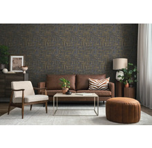 Woonkamer met donker behang met abstract patroon, bruine leren bank, lichte fauteuil, salontafel en vloerkleed in moderne stijl.
