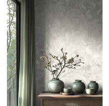 Vliesbehang met subtiel bladerpatroon in een lichte, natuurlijk ingerichte kamer met houten dressoir en keramieken vazen.