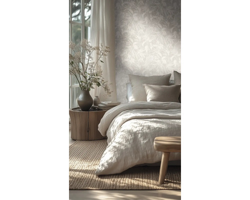 Lichte slaapkamer met vliesbehang met bladmotief, een bed met linnen beddengoed en een nachtkastje van een boomstam.