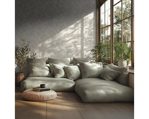 Moderne woonkamer met modulaire bank, veel kussens, behang met patroon, houten vloer, gevlochten poef en planten bij het zonnige raam.