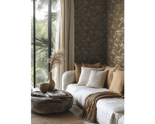 Vliesbehang met floraal patroon in aardetinten achter een bank met kussens en een rustieke boomstamtafel.