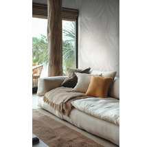 Lichte woonkamer met botanisch behang, een linnen bank met kussens en een rustieke houten balk.