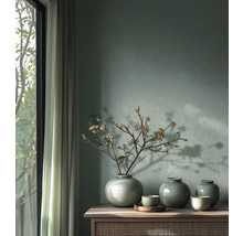 Muur met groene muurverf, drie keramische vazen met craquelé glazuur en takken op een houten dressoir naast een raam met gordijnen.