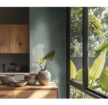 Moderne keuken met gestructureerde wand, houten kasten en werkblad. Daarop keramische kommen en een vaas. Groot venster met uitzicht op planten.