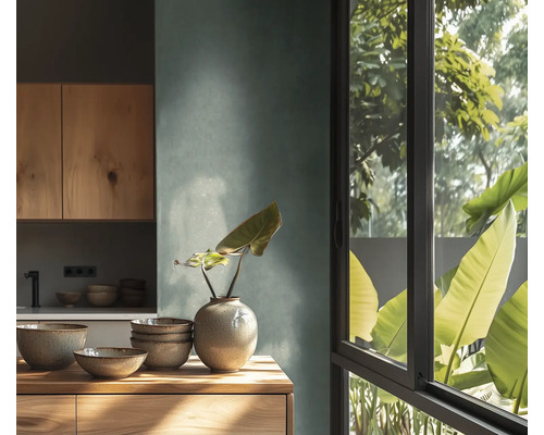 Moderne keuken met gestructureerde wand, houten kasten en werkblad. Daarop keramische kommen en een vaas. Groot venster met uitzicht op planten.