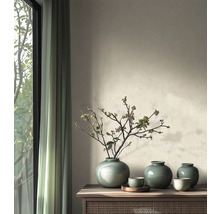 Minimalistische woonkamer met keramieken vazen met craquelé glazuur en gedroogde takken op een houten dressoir naast een raam.