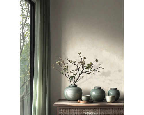 Minimalistische woonkamer met keramieken vazen met craquelé glazuur en gedroogde takken op een houten dressoir naast een raam.