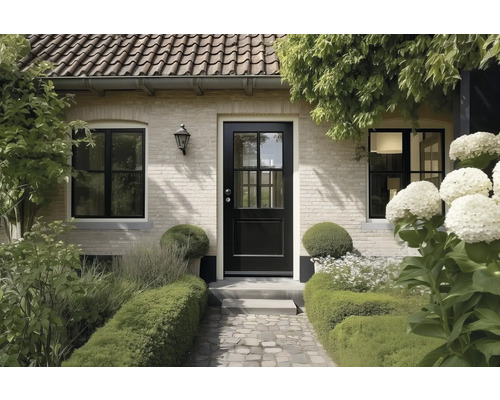 Huisingang met een zwarte voordeur met ruiten, lichte bakstenen muur, zwarte ramen en een bestraat pad door een tuin met hagen.
